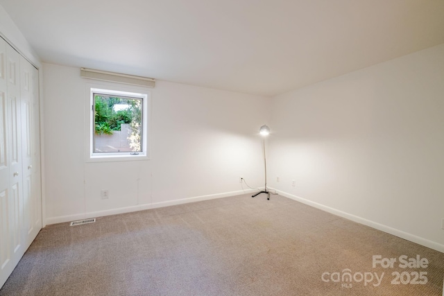 unfurnished room featuring baseboards, visible vents, and carpet