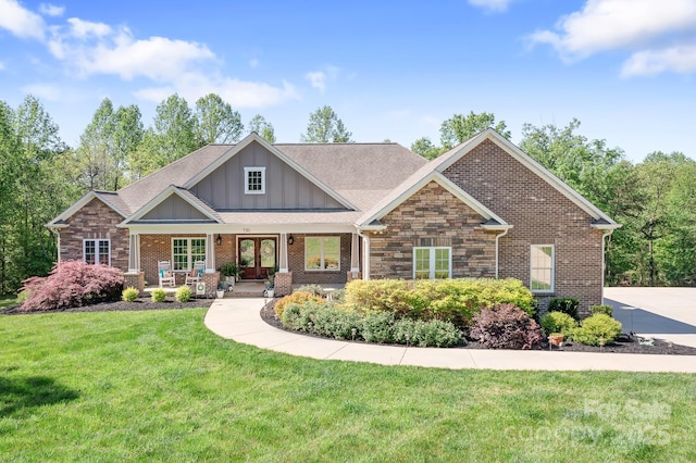 craftsman-style home featuring a front lawn, brick siding, board and batten siding, french doors, and covered porch