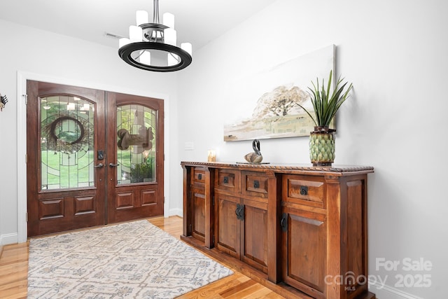 entryway with french doors, light wood-style floors, a chandelier, and visible vents