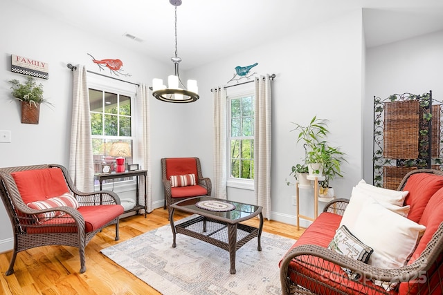 sitting room featuring visible vents, light wood-type flooring, baseboards, and an inviting chandelier