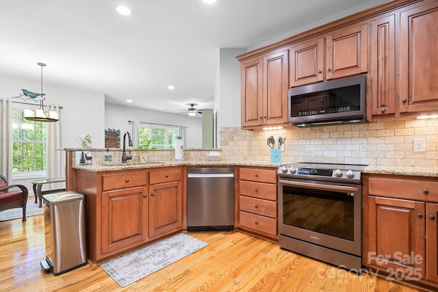 kitchen with a sink, a peninsula, stainless steel appliances, and light wood finished floors