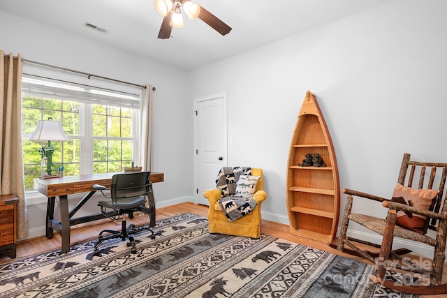 office with light wood-style floors, baseboards, a ceiling fan, and visible vents