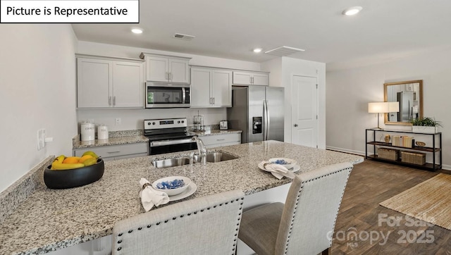 kitchen with dark wood-style flooring, a sink, a breakfast bar area, visible vents, and appliances with stainless steel finishes