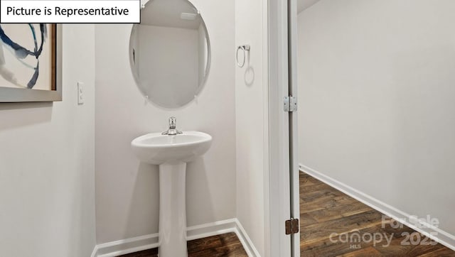 bathroom featuring baseboards, wood finished floors, and a sink