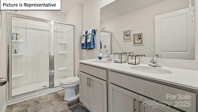 bathroom with stone finish floor, a shower stall, and a sink