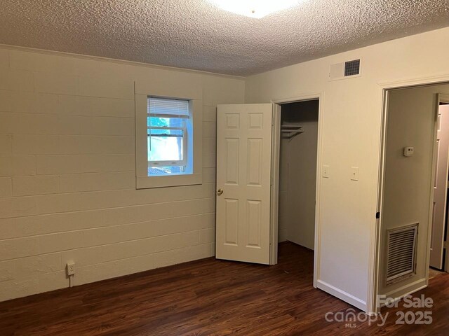116 Fairview St, Shelby, NC 28152 - unfurnished bedroom featuring dark wood-style floors, a textured ceiling, a closet, and concrete block wall