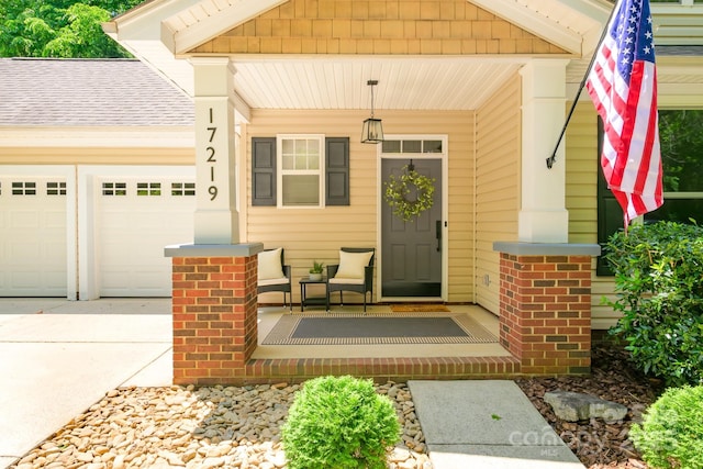 entrance to property with covered porch, a garage, driveway, and roof with shingles