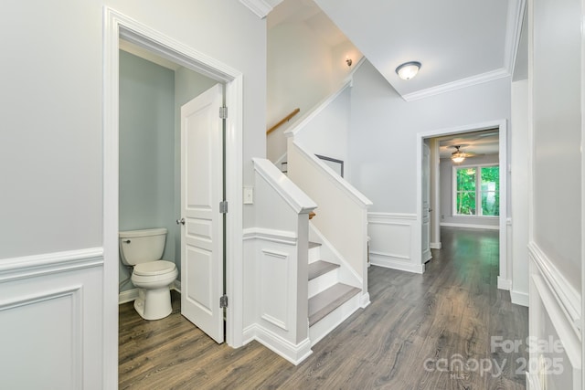 stairway with wood finished floors, ornamental molding, a ceiling fan, and baseboards