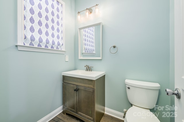 bathroom with baseboards, toilet, vanity, and wood finished floors