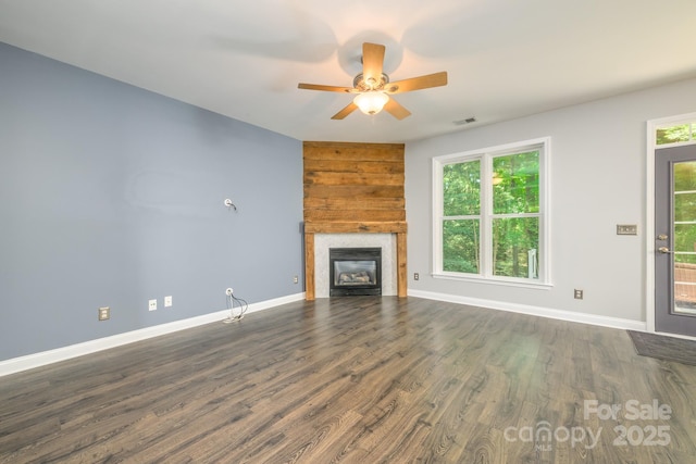 unfurnished living room with plenty of natural light, baseboards, and a glass covered fireplace