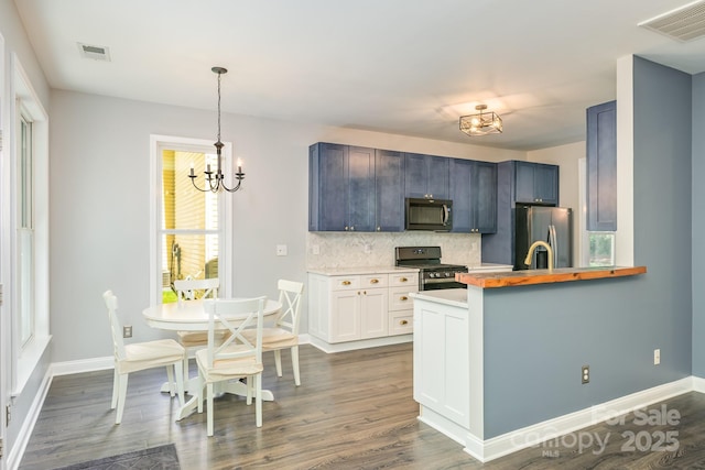kitchen featuring stainless steel appliances, decorative backsplash, a chandelier, and dark wood-style flooring