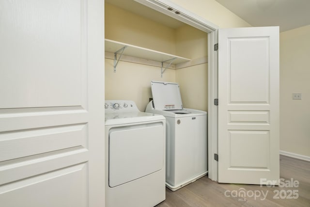 clothes washing area with independent washer and dryer and light wood-style floors