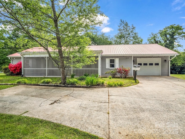 ranch-style home with concrete driveway, metal roof, a sunroom, and a garage