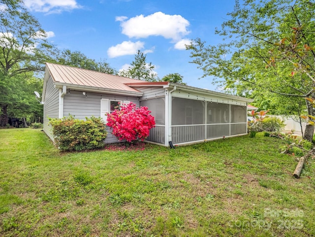 view of home's exterior with a sunroom, a lawn, and metal roof