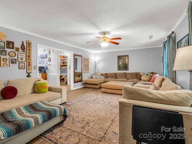 living room featuring a textured ceiling, ornamental molding, a ceiling fan, and wood finished floors