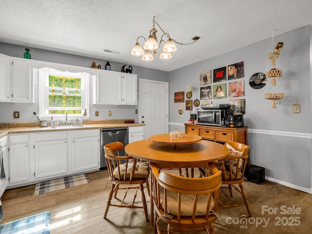 kitchen featuring white cabinets, appliances with stainless steel finishes, an inviting chandelier, a textured ceiling, and visible vents