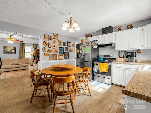 kitchen with a textured ceiling, light wood-type flooring, under cabinet range hood, stainless steel appliances, and white cabinetry