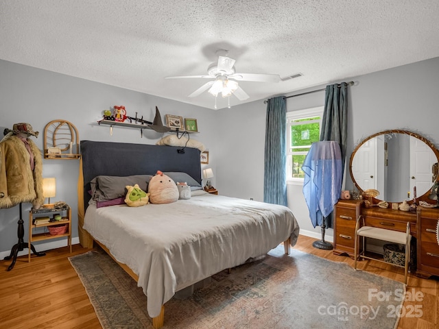 bedroom featuring visible vents, a textured ceiling, and wood finished floors