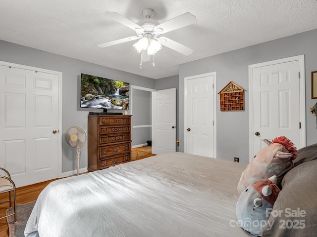 bedroom featuring baseboards, ceiling fan, a textured ceiling, and wood finished floors