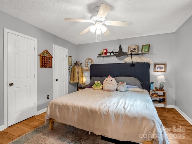 bedroom featuring baseboards, a ceiling fan, a textured ceiling, and wood finished floors