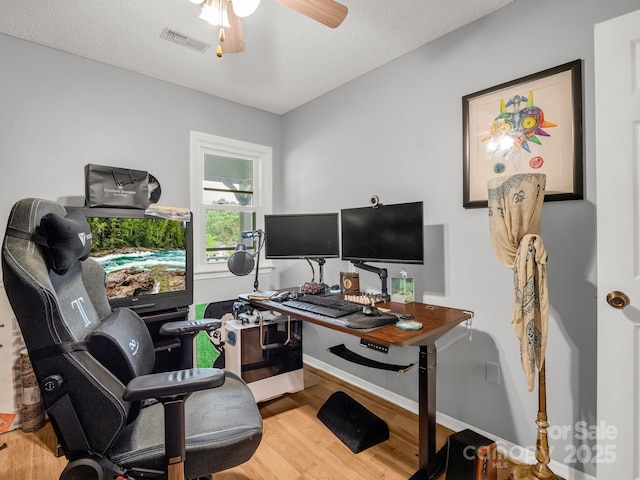 office space with visible vents, a ceiling fan, baseboards, and wood finished floors