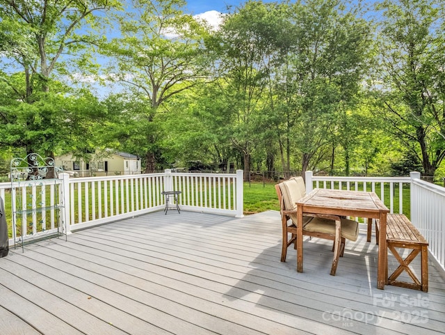 wooden deck featuring outdoor dining area, fence, and a yard