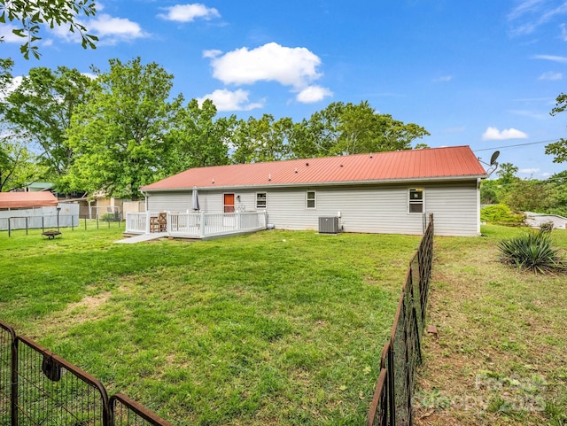 rear view of house with central AC unit, a fenced backyard, and a yard