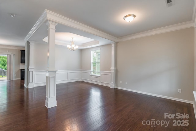 spare room featuring decorative columns, visible vents, an inviting chandelier, ornamental molding, and dark wood-type flooring