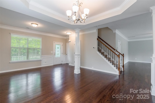 interior space featuring an inviting chandelier, ornamental molding, dark wood-style flooring, and ornate columns