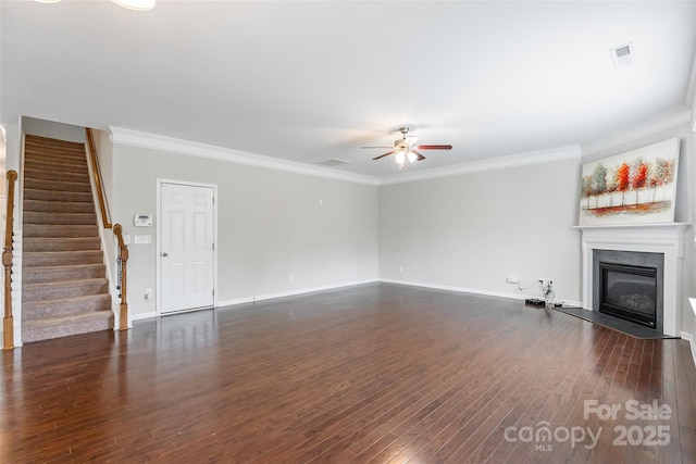 unfurnished living room featuring stairs, a ceiling fan, crown molding, and a glass covered fireplace