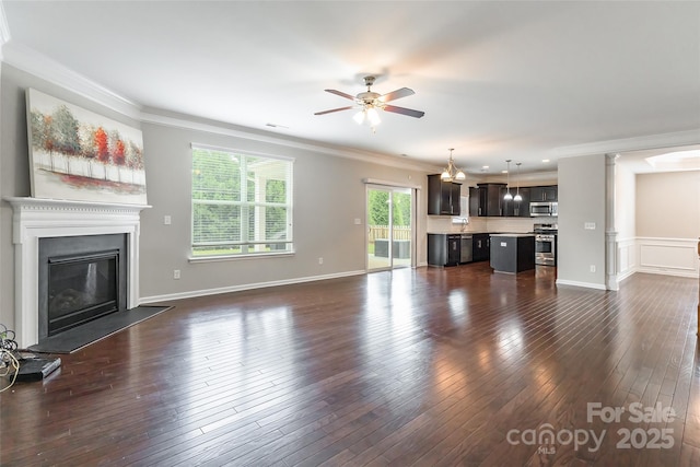 unfurnished living room with ceiling fan, a glass covered fireplace, ornamental molding, and dark wood-type flooring