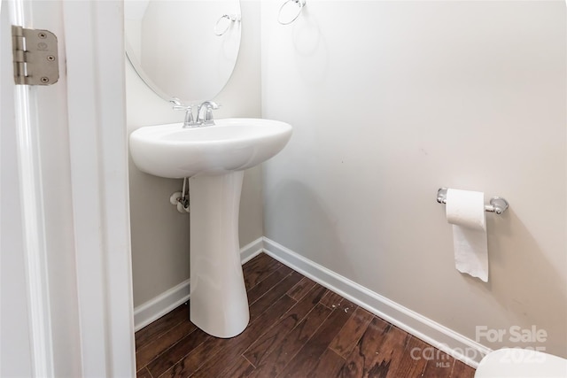 bathroom with baseboards, a sink, and wood finished floors