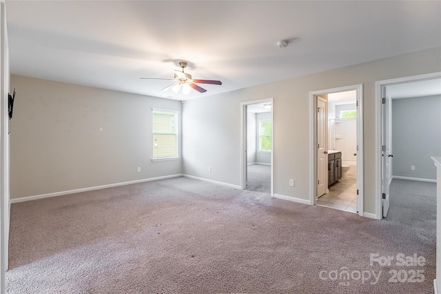 unfurnished bedroom with baseboards, ceiling fan, connected bathroom, and light colored carpet