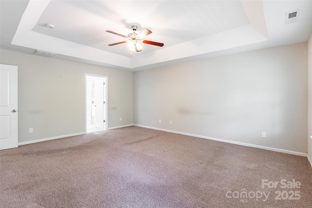 unfurnished room with a raised ceiling, ceiling fan, carpet flooring, and visible vents