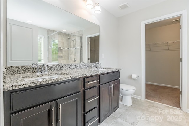 full bath with double vanity, a stall shower, a sink, toilet, and a spacious closet