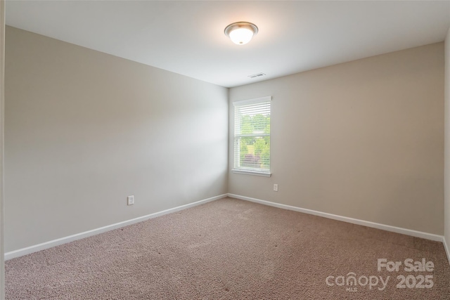 empty room featuring carpet floors, baseboards, and visible vents