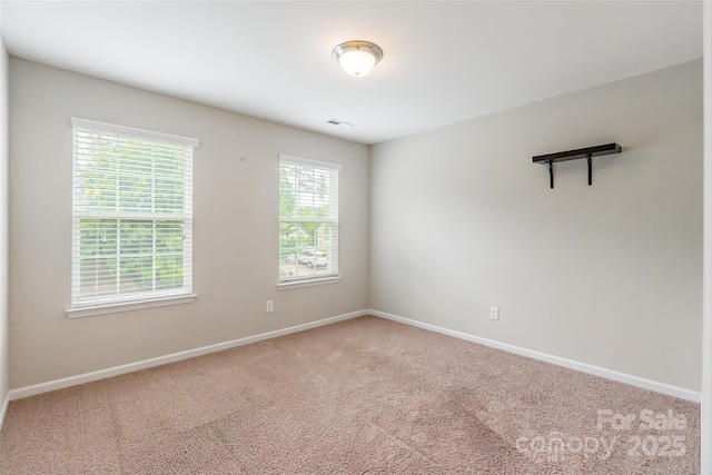 spare room with carpet floors, baseboards, and visible vents