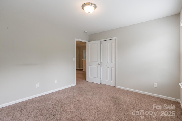unfurnished bedroom featuring carpet flooring, baseboards, and a closet
