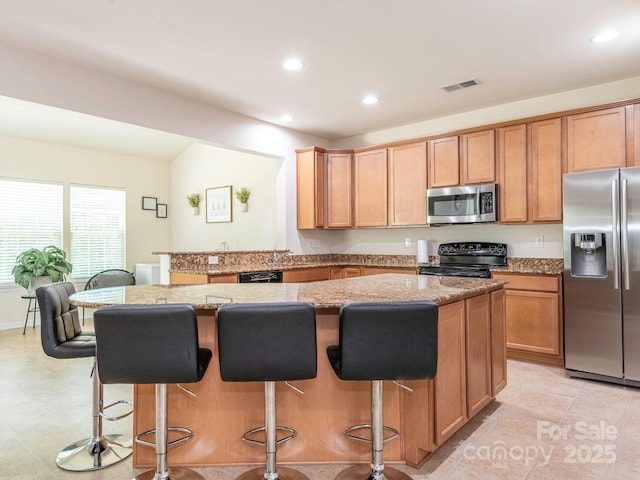 kitchen featuring a breakfast bar, black appliances, visible vents, recessed lighting, and light stone countertops