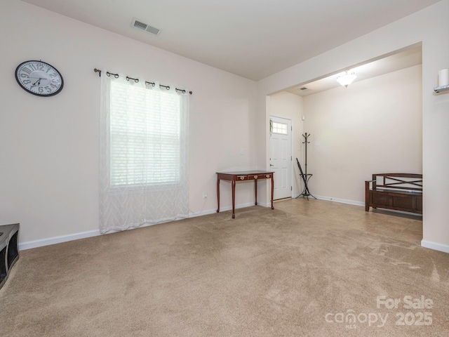 carpeted spare room featuring baseboards and visible vents
