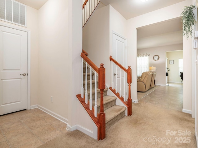 stairway featuring baseboards and visible vents