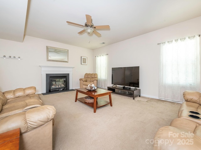 living area with ceiling fan, light carpet, baseboards, and a fireplace with flush hearth