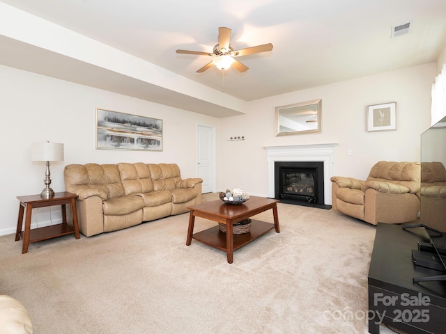 living area with a ceiling fan, baseboards, visible vents, a fireplace with flush hearth, and light carpet