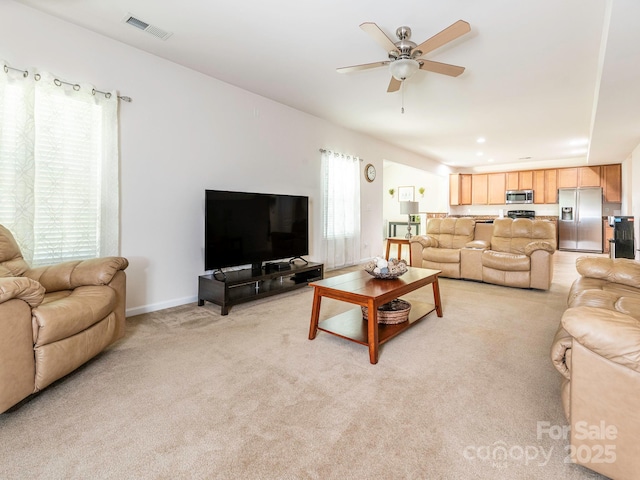 living area with light colored carpet, visible vents, baseboards, and a ceiling fan