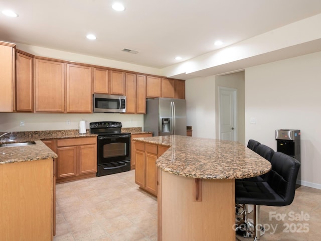 kitchen with stone counters, a breakfast bar area, recessed lighting, a center island, and stainless steel appliances