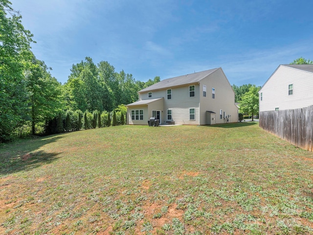 rear view of property with a yard and fence