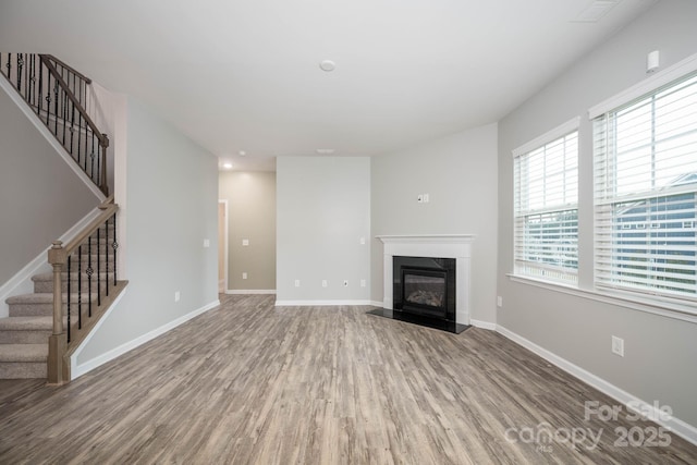 150 Falls Cove Dr, Troutman, NC 28166 - unfurnished living room featuring a premium fireplace, baseboards, wood finished floors, and stairway