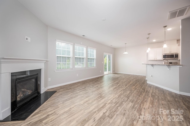 150 Falls Cove Dr, Troutman, NC 28166 - unfurnished living room featuring baseboards, visible vents, a glass covered fireplace, and light wood-type flooring