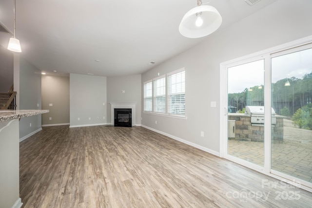 150 Falls Cove Dr, Troutman, NC 28166 - unfurnished living room with a glass covered fireplace, baseboards, stairs, and wood finished floors