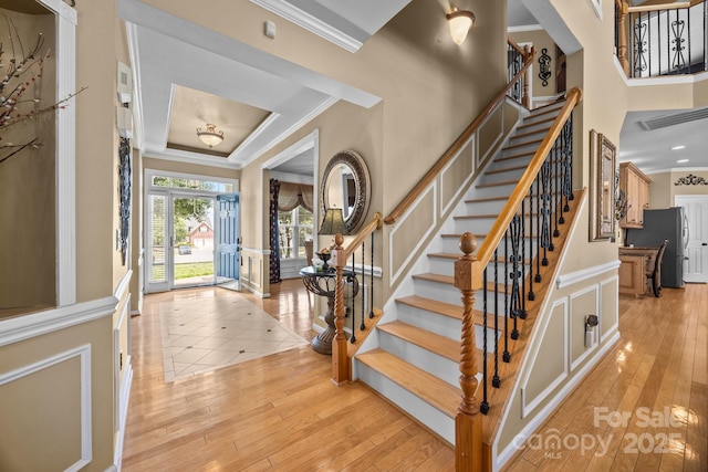 1900 Birchbrook Ct, Harrisburg, NC 28075 - foyer entrance featuring crown molding, stairway, light wood-style floors, a decorative wall, and a wainscoted wall